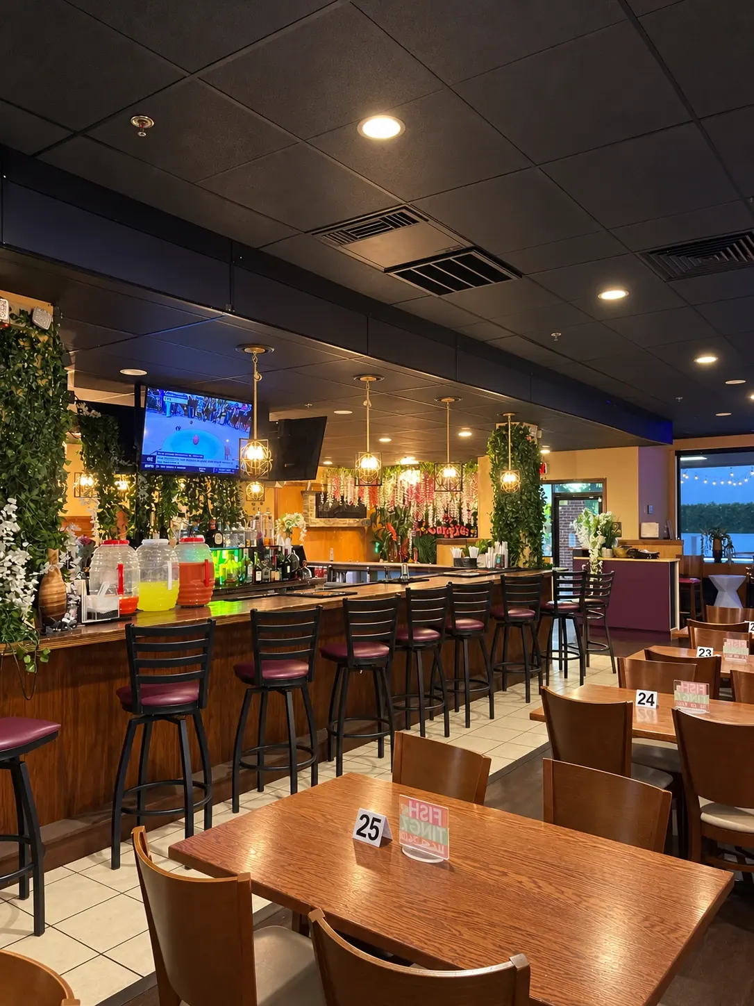 The bar and dining tables at Fish N Tingz, with greenery and warm pendant lights